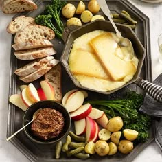 an assortment of food on a tray with bread, apples, potatoes and other foods