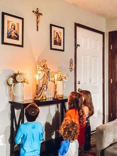 three children standing in front of a table with candles on it and pictures above them