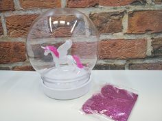 there is a pink glitter powder and a white plastic horse in a glass bowl on the table