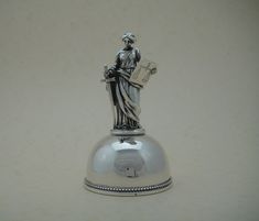 A silver table bell, the handle like Lady Justice. The heavy semicircular plain bell with a pearl rim decorated above the thickened lip, the handle like Lady Justice standing on a round base complete with sword and plaque on which a pair of scales is engraved, the symbols indicate jurisprudence. The table bell with a large silver clapper. The bell sounds great and is in top condition. The clapper is stamped with 800, the thickened lip of the bell is stamped with the letter V 800, 800/1000 silver Bell Sound, Lady Justice, Silver Table, Letter V, Scales, Flatware, Etsy Accessories, Electronic Accessories, Paper Party Supplies