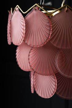 several pink umbrellas hanging from a gold colored chandelier in a dark room