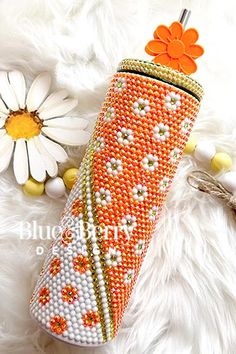 an orange and white beaded case with flowers on it sitting next to a flower