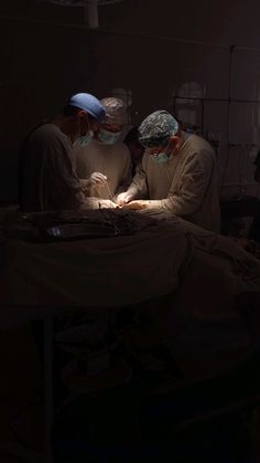 three doctors in scrubs are looking at something on a table with light coming from behind them