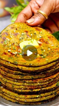 a stack of food sitting on top of a metal pan filled with green vegetables and sauce