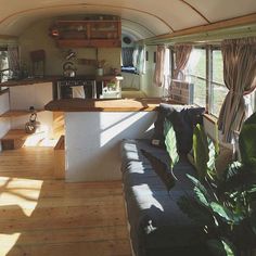 the interior of a tiny home with wood flooring and walls, windows, and couches