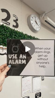 someone is holding up a sign that says use an alarm in front of a clock