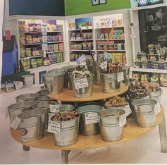 several metal buckets are stacked on a table in a grocery store with price tags hanging from them