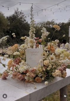 an arrangement of flowers on a table at a cemetery with string lights in the background