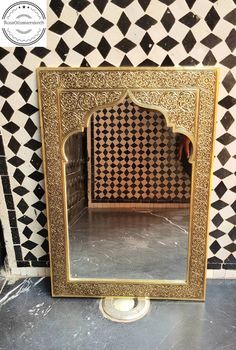 a mirror sitting on top of a tiled floor next to a wall with black and white tiles