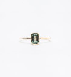 The leafy shimmer of a bright green sapphire is carefully set into a dainty bezel and handmade wire band in this Jennie Kwon Designs ring that's subtle yet hard to miss. Add a soft hint of color to your everyday style by wearing it alone, or pair it with a stack of textured gold bands on the same hand. Made in the U.S.A. All sizes made to order within 3-4 weeks of purchase. To inquire regarding alternate metal and gemstone options, please contact us. 14 karat gold set with one 4 mm x 6 mm (appro