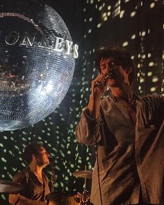 two men singing on stage in front of a disco ball with the words'dancing bears'written on it