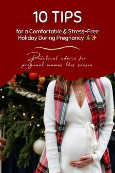 the pregnant woman is standing in front of a christmas tree with her hand on her belly