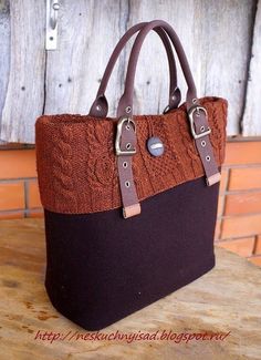 a brown and black handbag sitting on top of a wooden table next to a wall