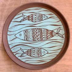 a wooden plate with fish painted on it