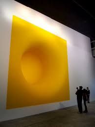 two people standing in front of a large yellow painting