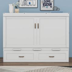 a white dresser with two pictures on the wall above it and a rug in front of it