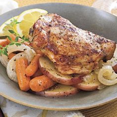 a plate with chicken, carrots and potatoes on it next to a glass of wine