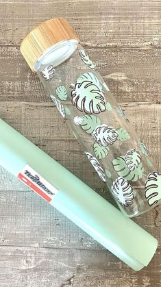 a green and white tumbler next to a bamboo lid on a wooden table with wood planks