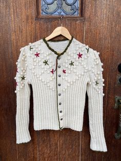 Here is a beautiful handmade  Austrian (believe Tyrolean) cardigan sweater with pewter buttons. If I am wrong on the Tyrolean please message me so I can update the listing!  Color is ivory along with green and red flowers/trim - perfect for Christmas! I am  Unsure of the yarns material and era.  This has been cleaned. As it's been formally owned and worn, mild fuzzing near hem and bottom of arm.  Please see measurements as this is handmade. Best for a smaller / petite person. The yarn expands so it gives some wiggle room.  Measurements:  Bust - 32 inches Hem - 28 inches  Length - 21.5 inches Arm - Collar to wrist - 29 inches  All sales final! For additional questions, images or issues with your order please contact me!   Vintage products may not be perfect so I give honest reviews and crit Handmade Vintage Cardigan For Winter, Handmade Vintage Winter Cardigan, White Wool Sweater With Button Closure, Bohemian Winter Cardigan With Buttons, Bohemian Winter Sweater With Buttons, Handmade Fitted Winter Cardigan, Handmade Cream Cardigan For Winter, Tyrolean Cardigan, Room Measurements