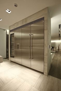 a modern kitchen with stainless steel refrigerators and wood flooring, along with white walls