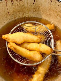 some fried food is being cooked in a frying pan with tongs on the side