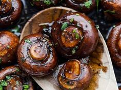 cooked mushrooms on a wooden spoon with parsley in the middle, ready to be eaten