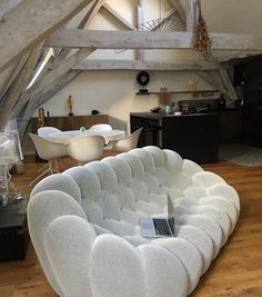 a living room filled with white furniture and wooden flooring next to an open kitchen