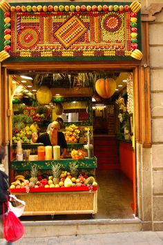 a woman walking past a fruit stand on the street