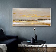 a living room with a couch, table and painting hanging on the wall above it