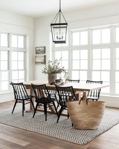 a dining room table with chairs and a basket on the rug in front of it