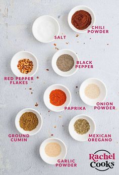 the ingredients for chili seasoning in small white bowls on a gray background with red pepper, black pepper, paprika, and mexican oregano