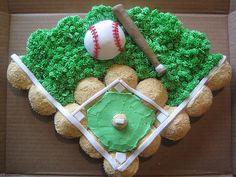 a cake in the shape of a baseball field with a bat and ball on top