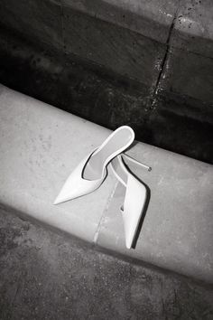 a pair of white shoes sitting on top of a cement bench next to a wall