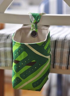 a green and white bag hanging from the side of a bed