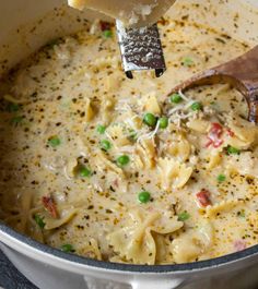 a ladle scooping some food out of a pot filled with pasta and peas