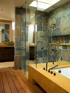 a bathroom with stone walls and wooden flooring next to a walk in shower area