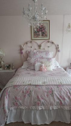 a white bed with pink flowers on it and a chandelier