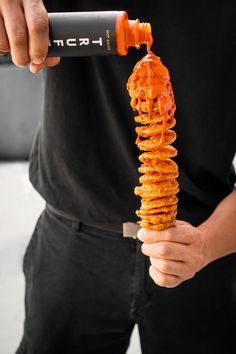 a man is holding a giant stack of pancakes with caramel syrup on it and an orange sauce pouring over the top