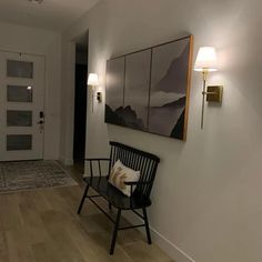 a black chair sitting on top of a hard wood floor next to a white wall