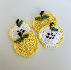 two crocheted apples sitting on top of a white table next to each other