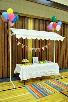 a table topped with cake and balloons on top of a hard wood floor next to a wall