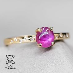 a close up of a ring with a pink stone on the front and white stones on the back