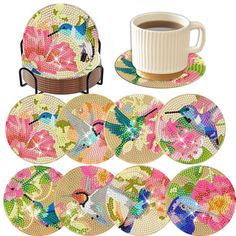 a set of six plates with birds and flowers on them, next to a cup of coffee