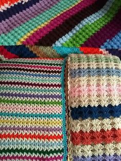 multicolored crocheted blanket laying next to each other on top of a bed