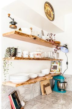 a kitchen counter with plates and bowls on it next to a wall mounted shelf filled with pots and pans