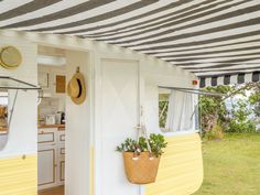 a yellow and white striped awning next to a kitchen area with potted plants