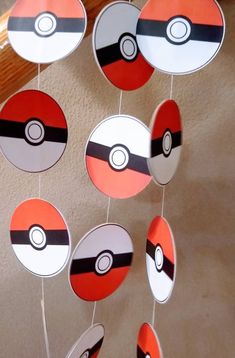 some paper balls are hanging from the ceiling with pokeballs on them and one is red, white, and black