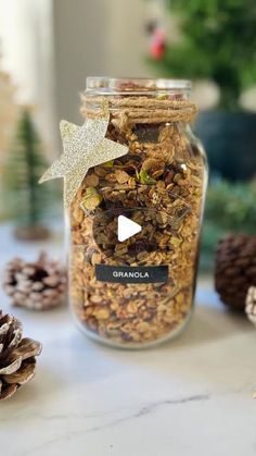 a jar filled with granola sitting on top of a table next to pine cones