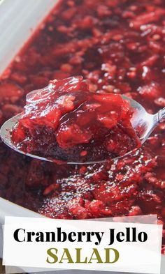 cranberry jello salad in a white bowl with a spoon full of it