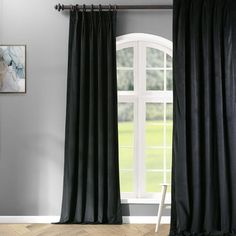 black curtains hanging in front of an open window with white trim and wood flooring